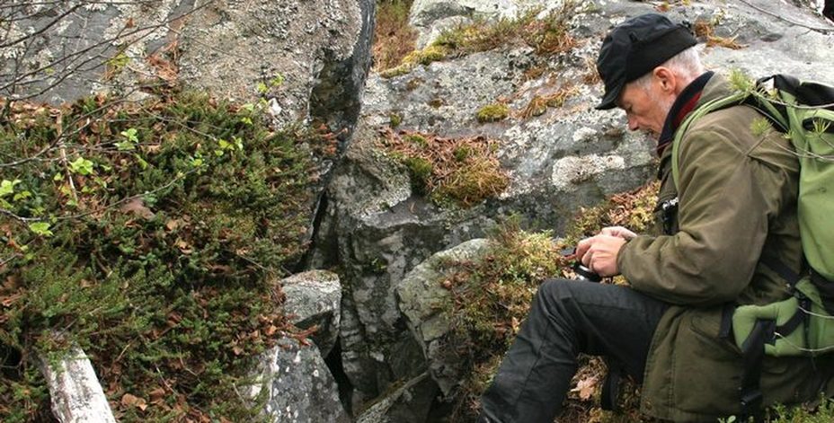 Bild på man sittandes utomhus i naturen.